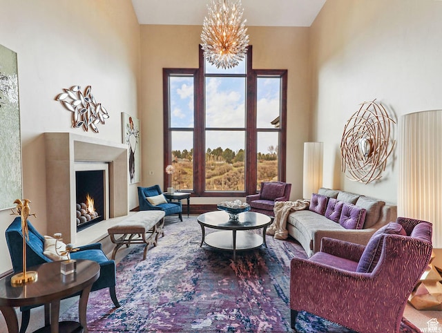 living area with a lit fireplace, a chandelier, and wood finished floors