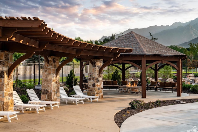 view of property's community featuring a mountain view, outdoor lounge area, a patio, fence, and a gazebo
