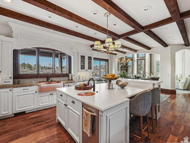 kitchen with a sink, arched walkways, a chandelier, dark wood finished floors, and beamed ceiling