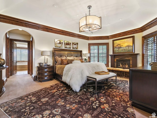 bedroom with multiple windows, crown molding, a glass covered fireplace, arched walkways, and baseboards