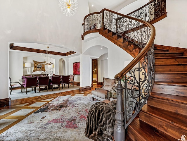 stairway with arched walkways, a towering ceiling, and baseboards