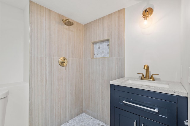 bathroom with a tile shower, vanity, and toilet
