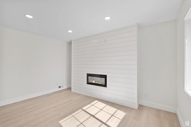 unfurnished living room with light wood-type flooring, a fireplace, recessed lighting, and baseboards