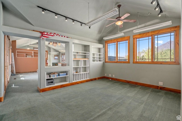 spare room with rail lighting, vaulted ceiling, baseboards, carpet flooring, and healthy amount of natural light
