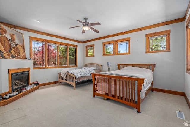 bedroom with carpet flooring, baseboards, a glass covered fireplace, and a ceiling fan