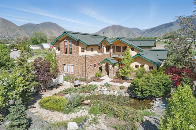 view of front of house with stone siding, a mountain view, and stucco siding