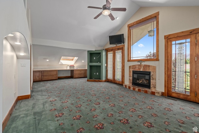 unfurnished living room with carpet, ceiling fan, a tiled fireplace, baseboards, and high vaulted ceiling