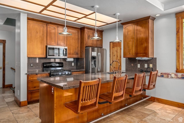 kitchen with stainless steel appliances, a sink, baseboards, a peninsula, and tasteful backsplash