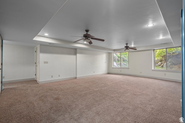 carpeted spare room with baseboards, recessed lighting, ceiling fan, and a tray ceiling