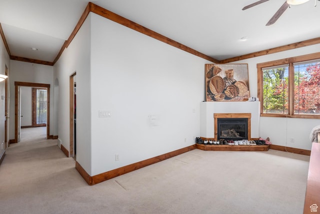 unfurnished living room featuring light carpet, a glass covered fireplace, and baseboards