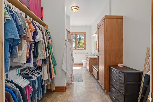 walk in closet featuring a sink and stone finish flooring