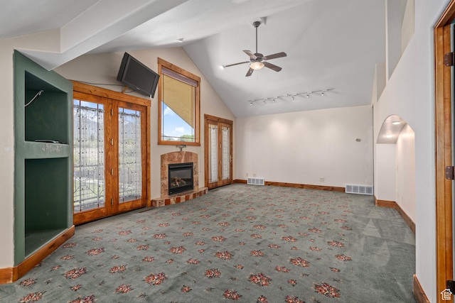 unfurnished living room featuring vaulted ceiling, carpet floors, a ceiling fan, a tile fireplace, and baseboards