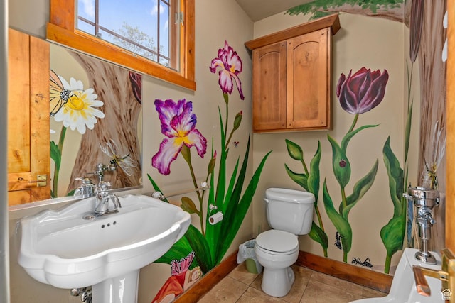 bathroom with toilet, a sink, tile patterned floors, and baseboards