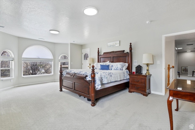 bedroom with light colored carpet, baseboards, and a textured ceiling