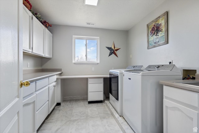 clothes washing area featuring cabinet space, washer and dryer, light marble finish flooring, a textured ceiling, and baseboards