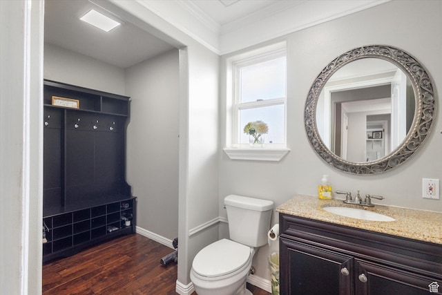bathroom with wood finished floors, toilet, vanity, crown molding, and baseboards