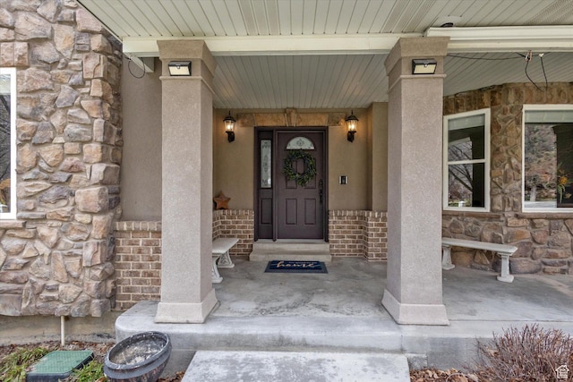 entrance to property featuring stone siding and a porch