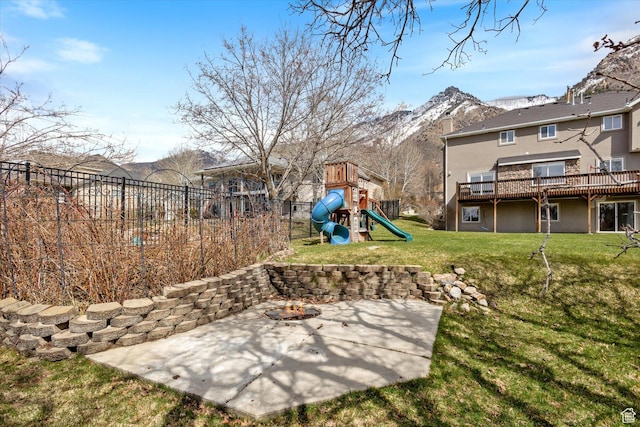 view of yard with a patio area, a deck with mountain view, a playground, and an outdoor fire pit