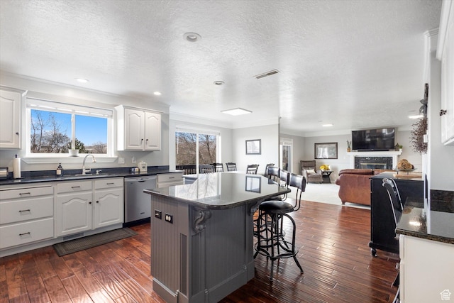 kitchen with dishwasher, ornamental molding, a center island, a breakfast bar area, and white cabinetry