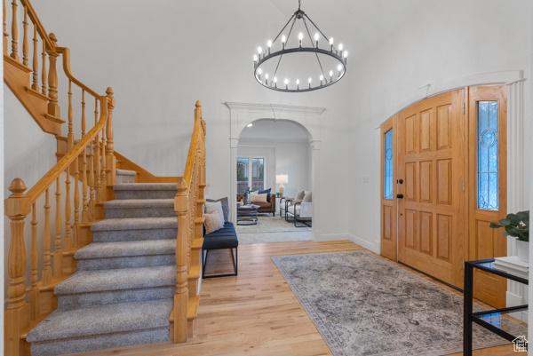 441 N Palisades Dr, Orem, UT 84097 - entrance foyer with arched walkways, stairs, wood finished floors, a high ceiling, and a chandelier