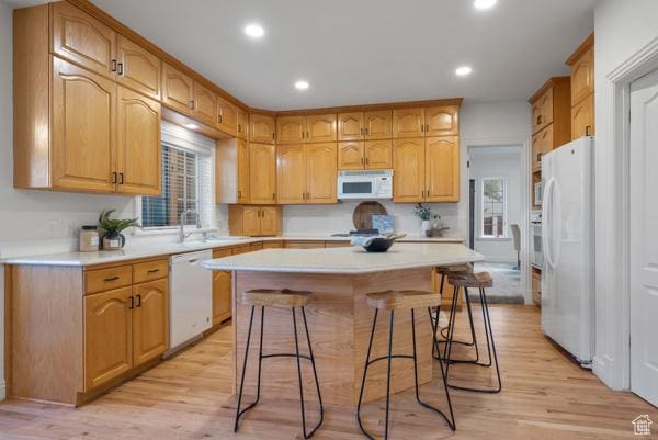 441 N Palisades Dr, Orem, UT 84097 - kitchen with white appliances, a breakfast bar area, light countertops, light wood-style floors, and a kitchen island