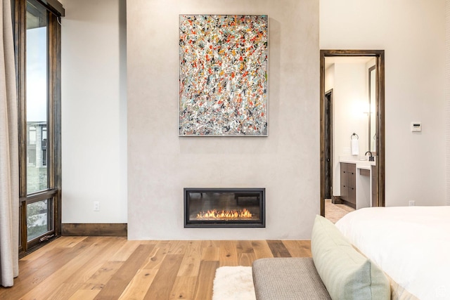 6110 E Blue Wing Loop, Kamas, UT 84036 - bedroom featuring wood finished floors, a glass covered fireplace, baseboards, and ensuite bath
