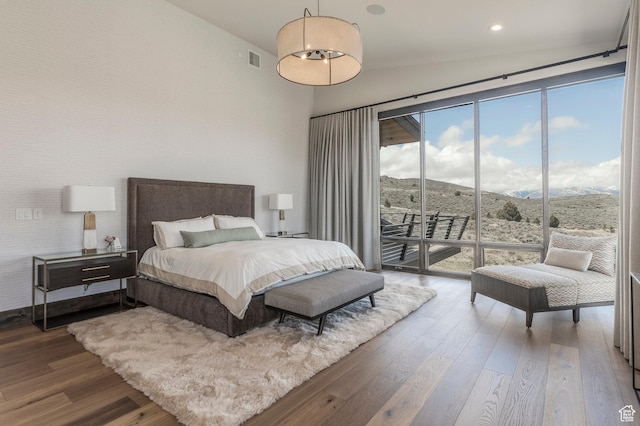 bedroom with access to exterior, hardwood / wood-style floors, and a mountain view