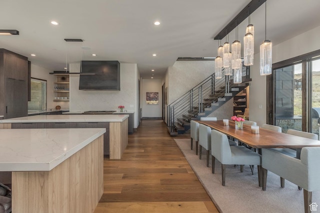 kitchen featuring modern cabinets, a center island, wood finished floors, recessed lighting, and exhaust hood