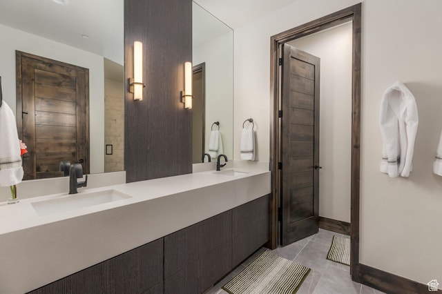 bathroom with double vanity, tile patterned floors, and baseboards