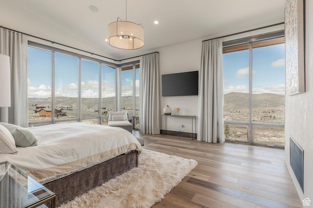 bedroom featuring access to outside, multiple windows, wood finished floors, vaulted ceiling, and recessed lighting