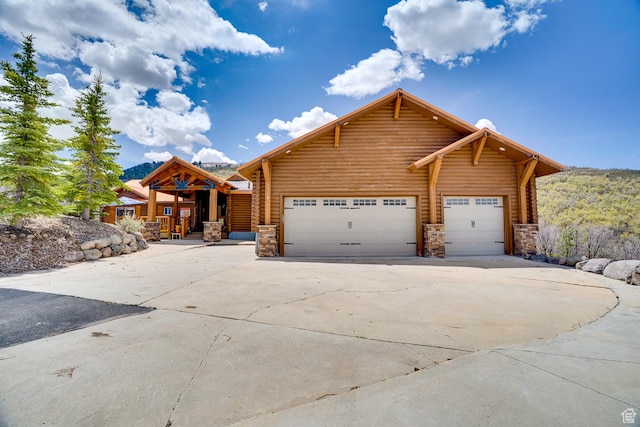 9174 Deer Creek Dr, Heber City, UT 84032 - cabin with stone siding, driveway, and an attached garage