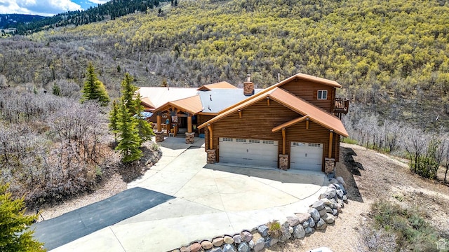 9174 Deer Creek Dr, Heber City, UT 84032 - view of front of property with a wooded view, a chimney, stone siding, and driveway