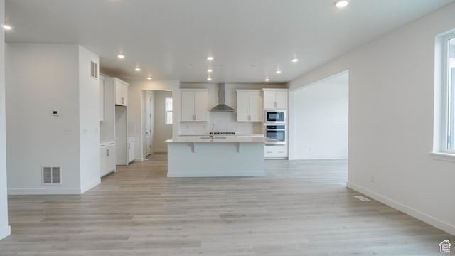5488 N Trailside Unit 431, Eagle Mountain, UT 84005 - kitchen featuring wall chimney exhaust hood, open floor plan, stainless steel oven, white cabinetry, and a kitchen island with sink