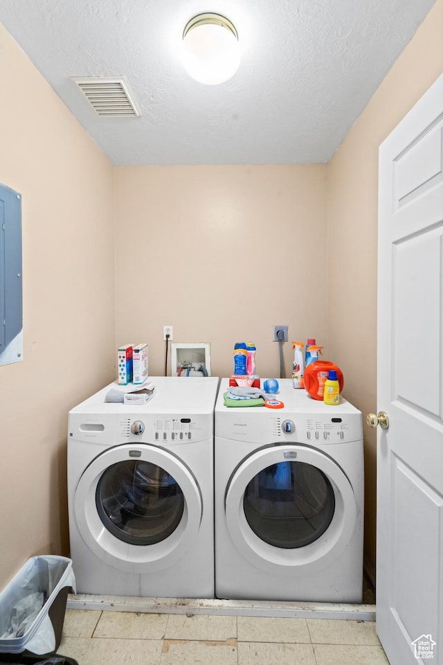 washroom with separate washer and dryer, electric panel, and a textured ceiling