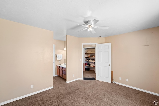 unfurnished bedroom featuring carpet floors, a walk in closet, a closet, and baseboards
