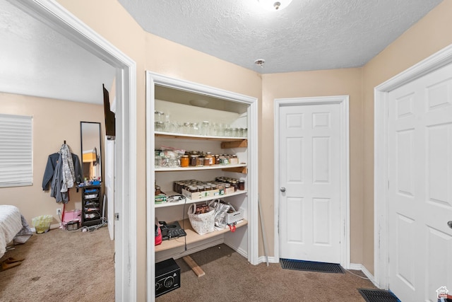 hall with carpet flooring, a textured ceiling, and baseboards