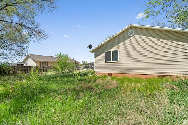 view of side of home featuring crawl space and fence