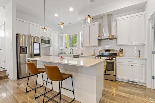 10243 S Silver Mine Rd W, South Jordan, UT 84009 - kitchen featuring stainless steel appliances, wall chimney exhaust hood, a breakfast bar area, light wood-type flooring, and a center island