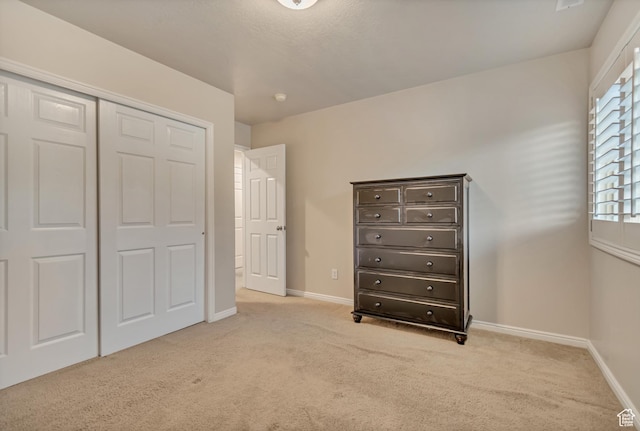 unfurnished bedroom with light carpet, baseboards, and a closet
