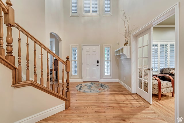 foyer entrance featuring wood finished floors, baseboards, stairway, and a towering ceiling