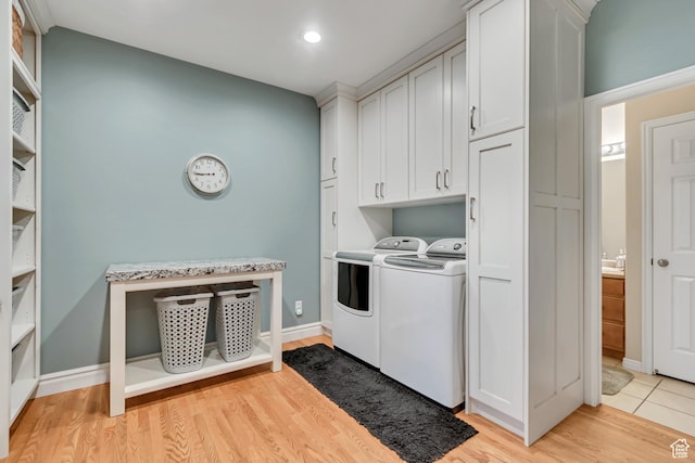 laundry room featuring washer and clothes dryer, cabinet space, light wood-style flooring, and recessed lighting