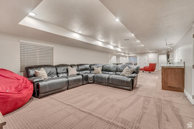 living area featuring light carpet, a textured ceiling, recessed lighting, baseboards, and a raised ceiling