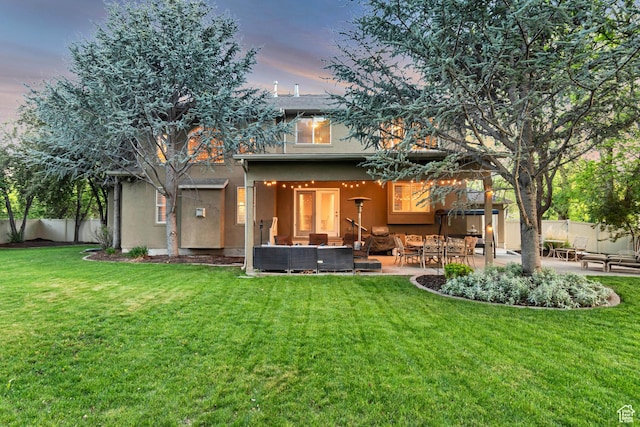 back of house at dusk featuring stucco siding, outdoor lounge area, and a patio area