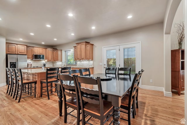 dining room featuring light wood-style flooring, recessed lighting, baseboards, french doors, and arched walkways