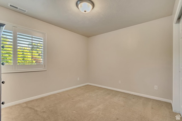 unfurnished room featuring light colored carpet, baseboards, and a textured ceiling