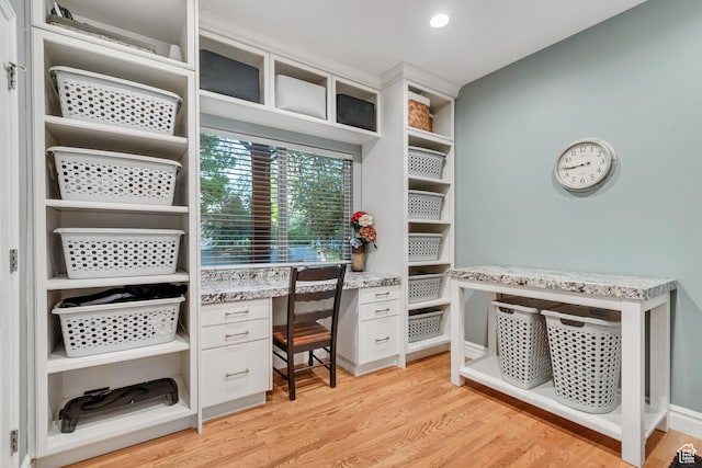 walk in closet with light wood finished floors and built in desk