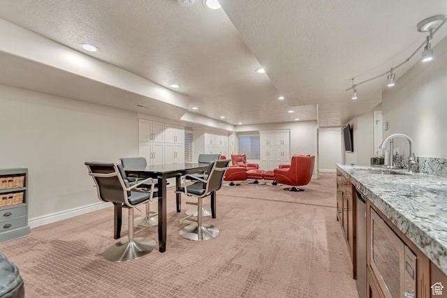 dining room with light colored carpet, a textured ceiling, baseboards, recessed lighting, and bar with sink