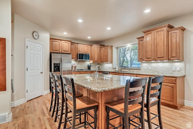kitchen featuring appliances with stainless steel finishes, a sink, light wood-type flooring, a breakfast bar area, and recessed lighting