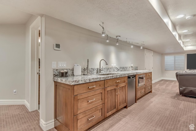 kitchen featuring a sink, light carpet, appliances with stainless steel finishes, brown cabinets, and a textured ceiling