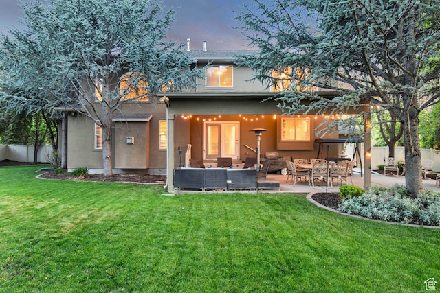 back of property at dusk with stucco siding, a patio area, and an outdoor living space